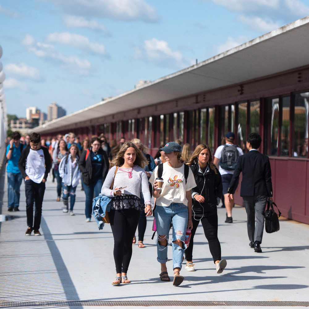 Students walk across the Washington Avenue Bridge on a sunny day.